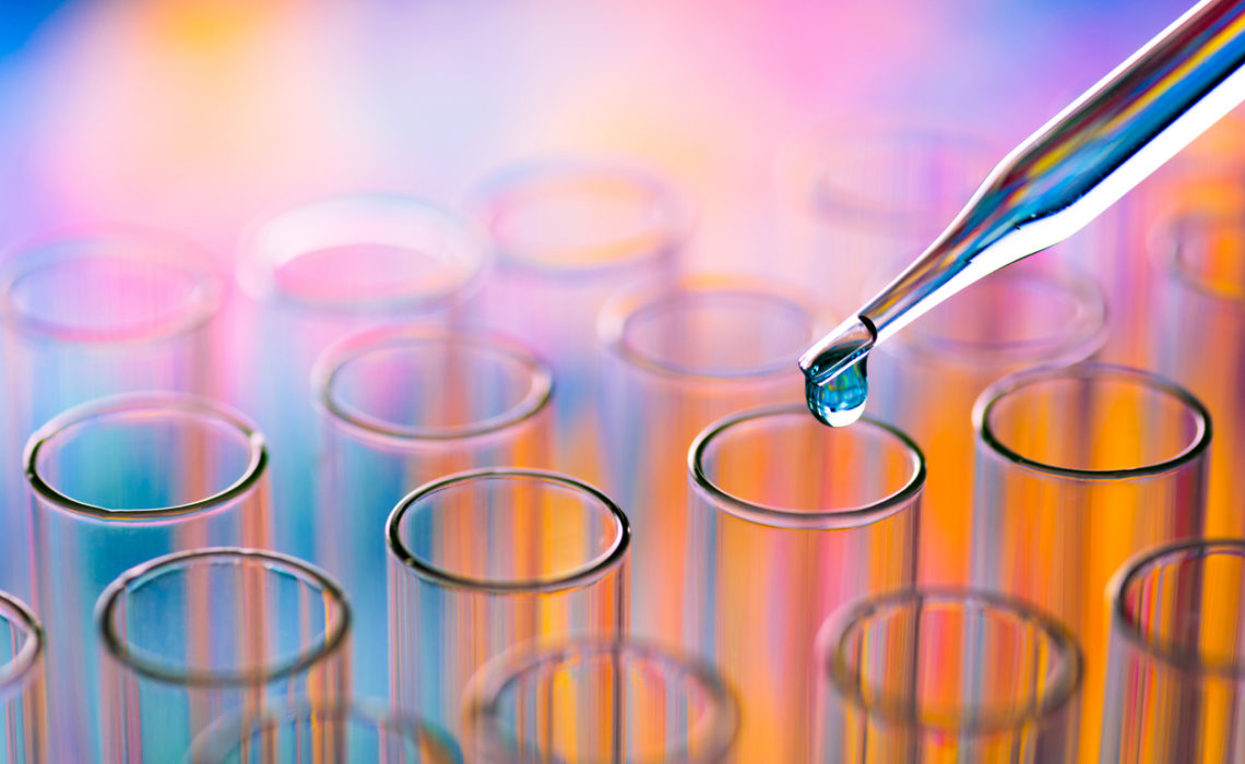 Close-Up Of Rainbow-filled Pipette Dripping Chemical In A Test Tube At A Laboratory