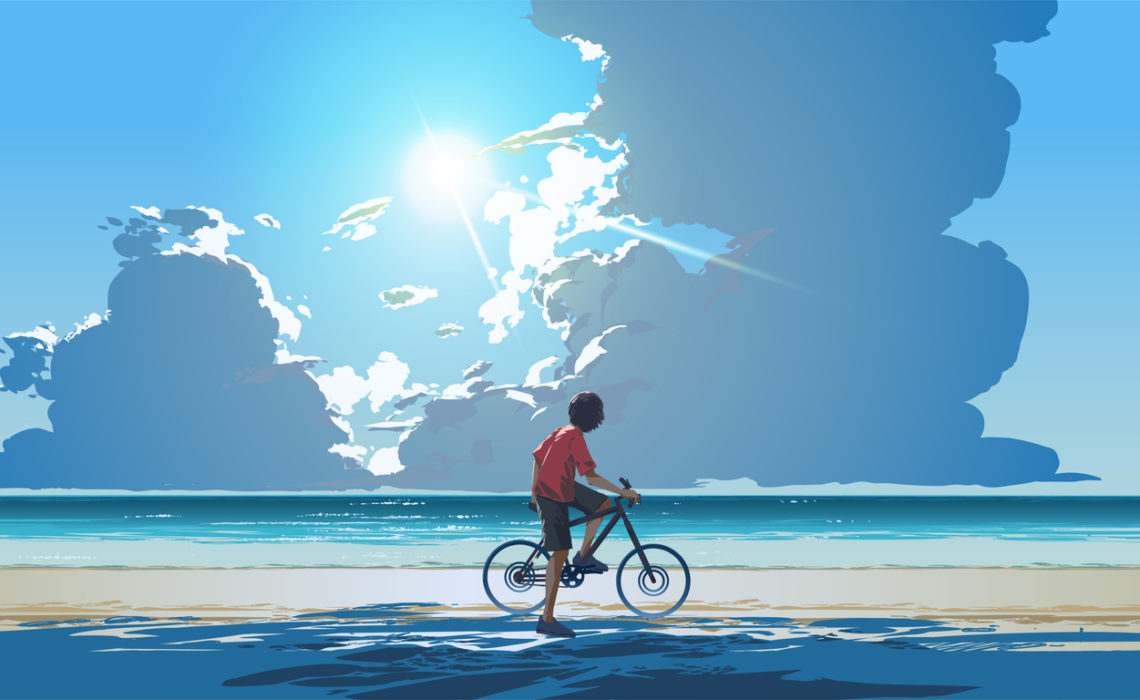 Boy with ear defenders sitting on a bike looking out at the sea and all the possibilities.