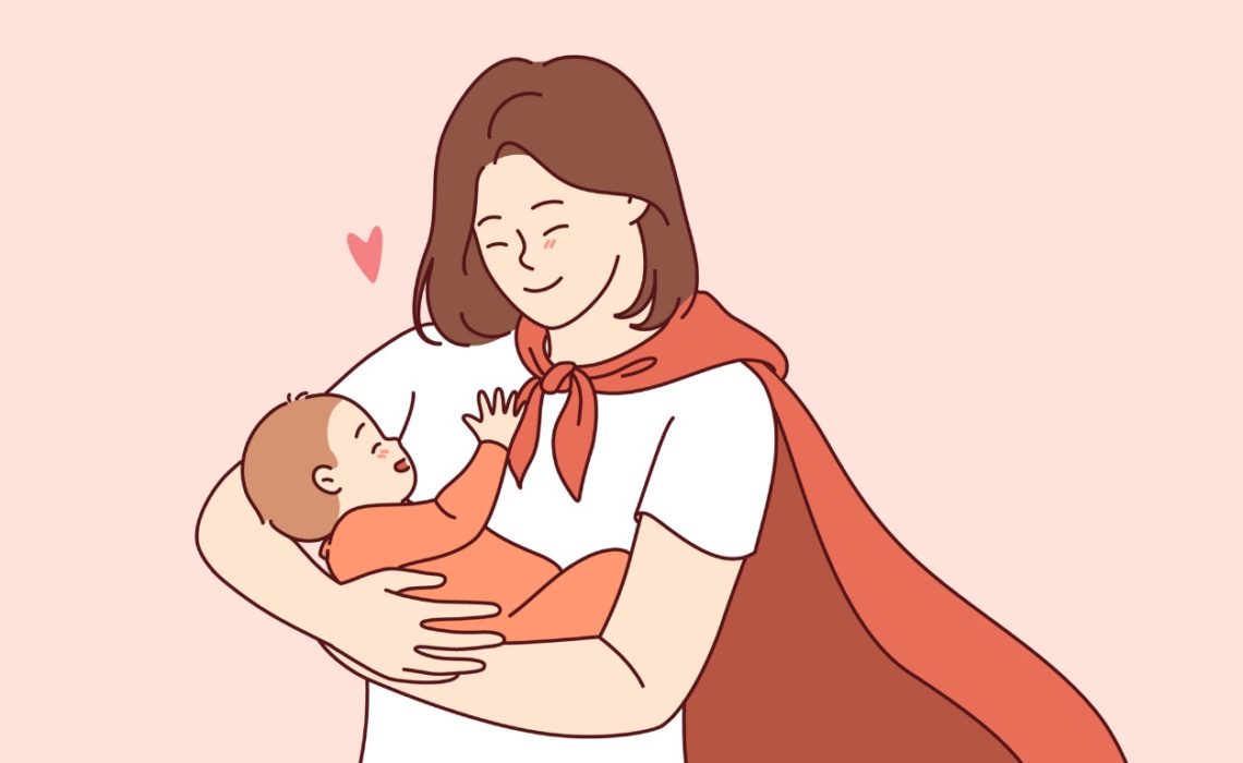 A mum with brown shoulder-length hair in a slightly off-centre red cape holding onto her baby looking at him lovingly.